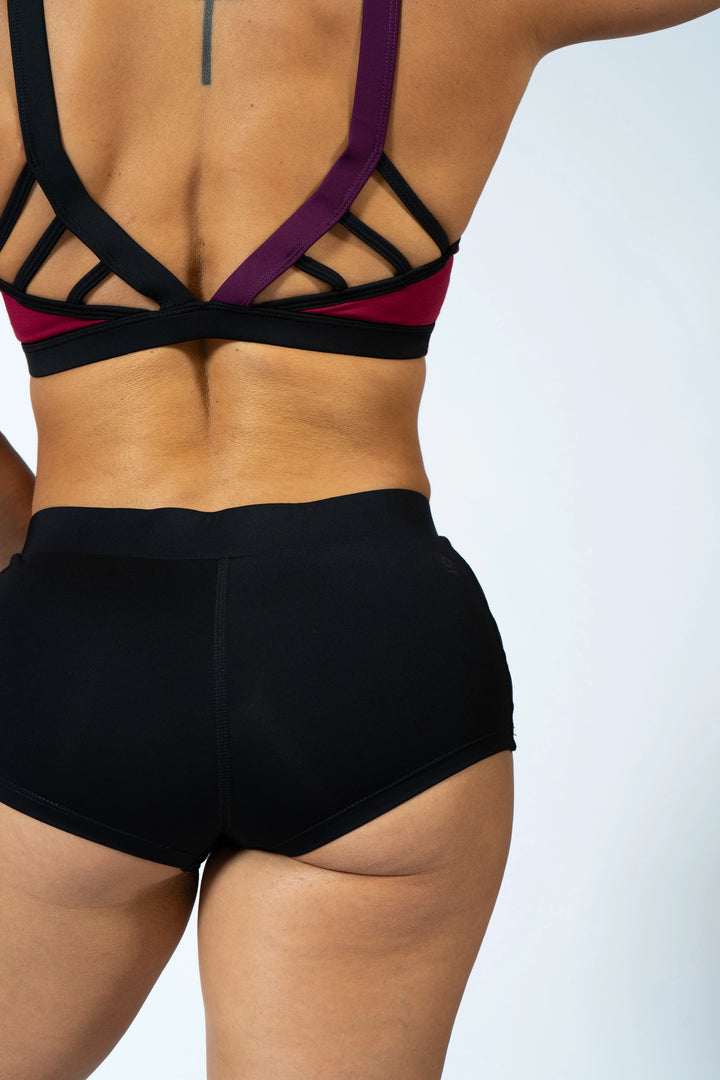 Woman wearing magenta sports bra and black shorts  on a plain background #color_black