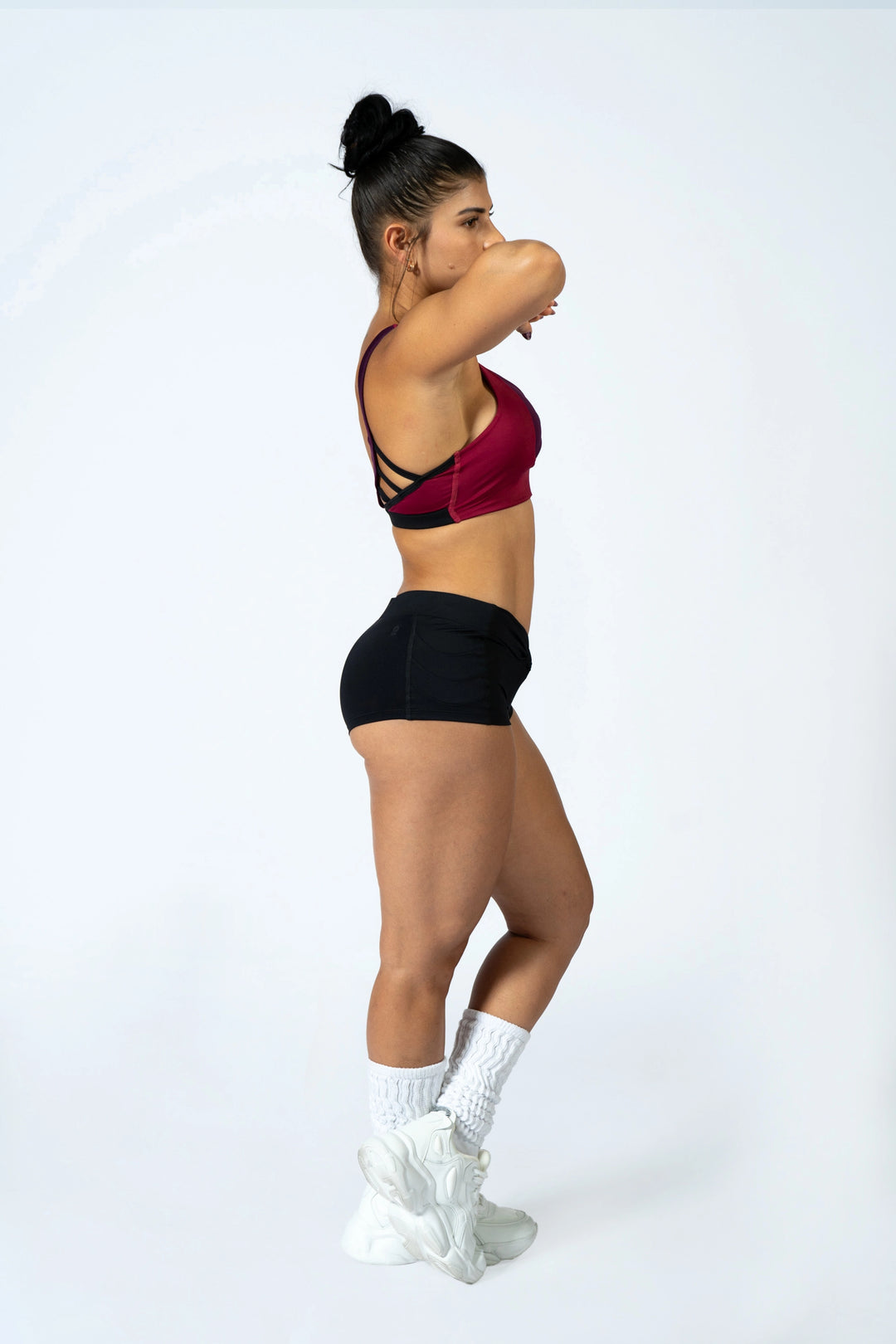 Woman wearing magenta sports bra and black shorts  on a plain background #color_black