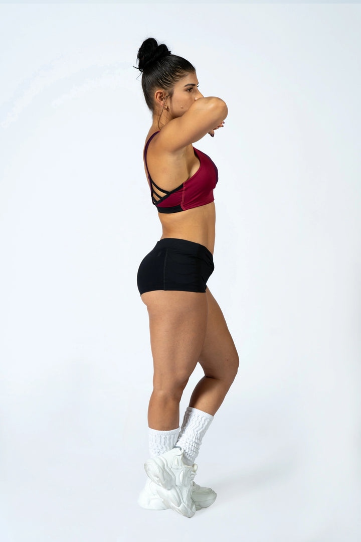 Woman wearing magenta sports bra and black shorts  on a plain background #color_black