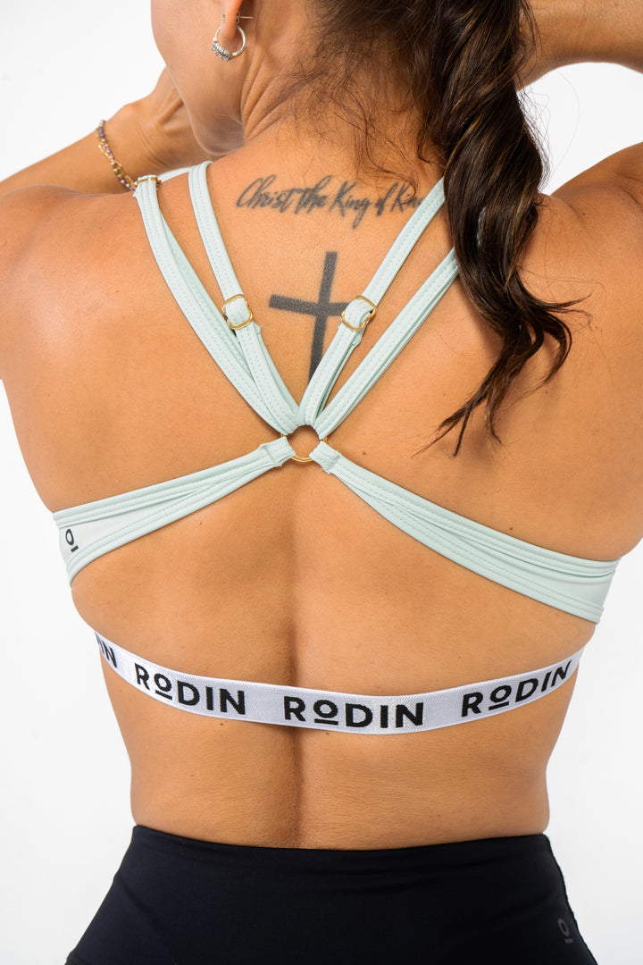 Person wearing a mint sports bra with 'Rodin' branding on a white background #color_mint
