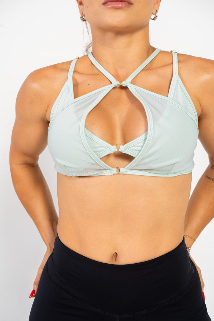 Woman wearing a mint sports bra and black leggings on a white background #color_mint