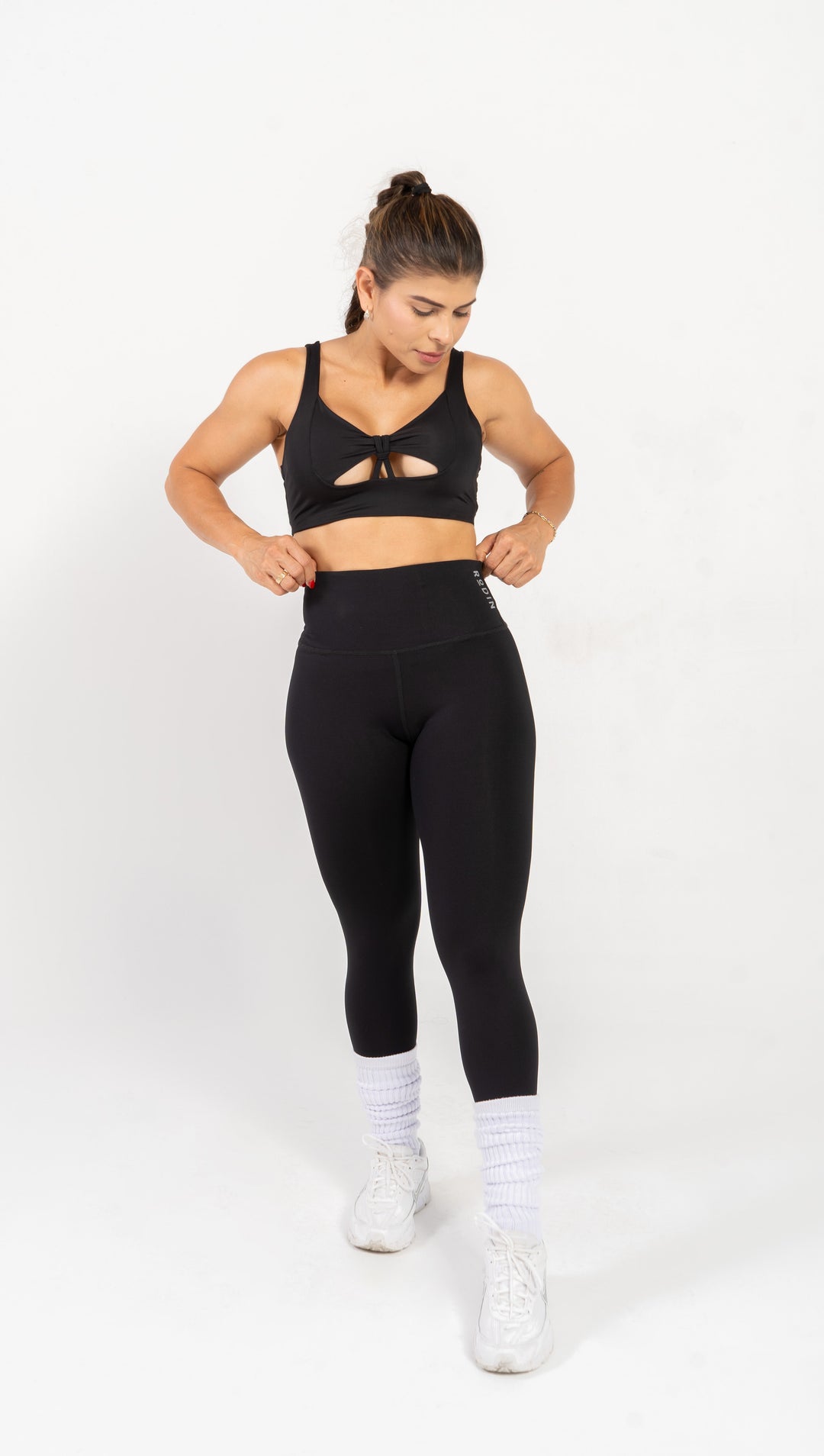 Woman wearing black athletic top and leggings on a white background #color_black