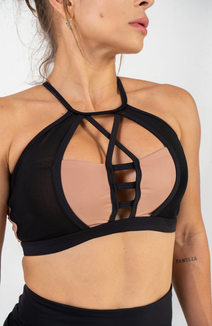 Black sports bra with mesh panels worn by a person on a plain background