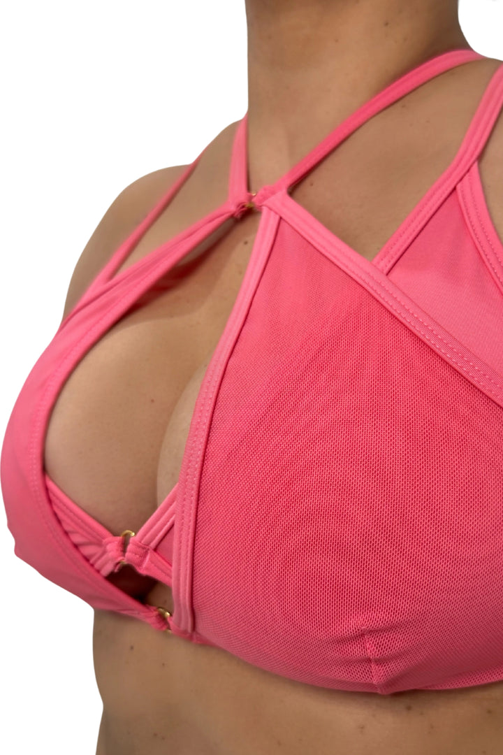 Close-up of a rose pink sports bra with criss-cross straps on a white background #color_rose