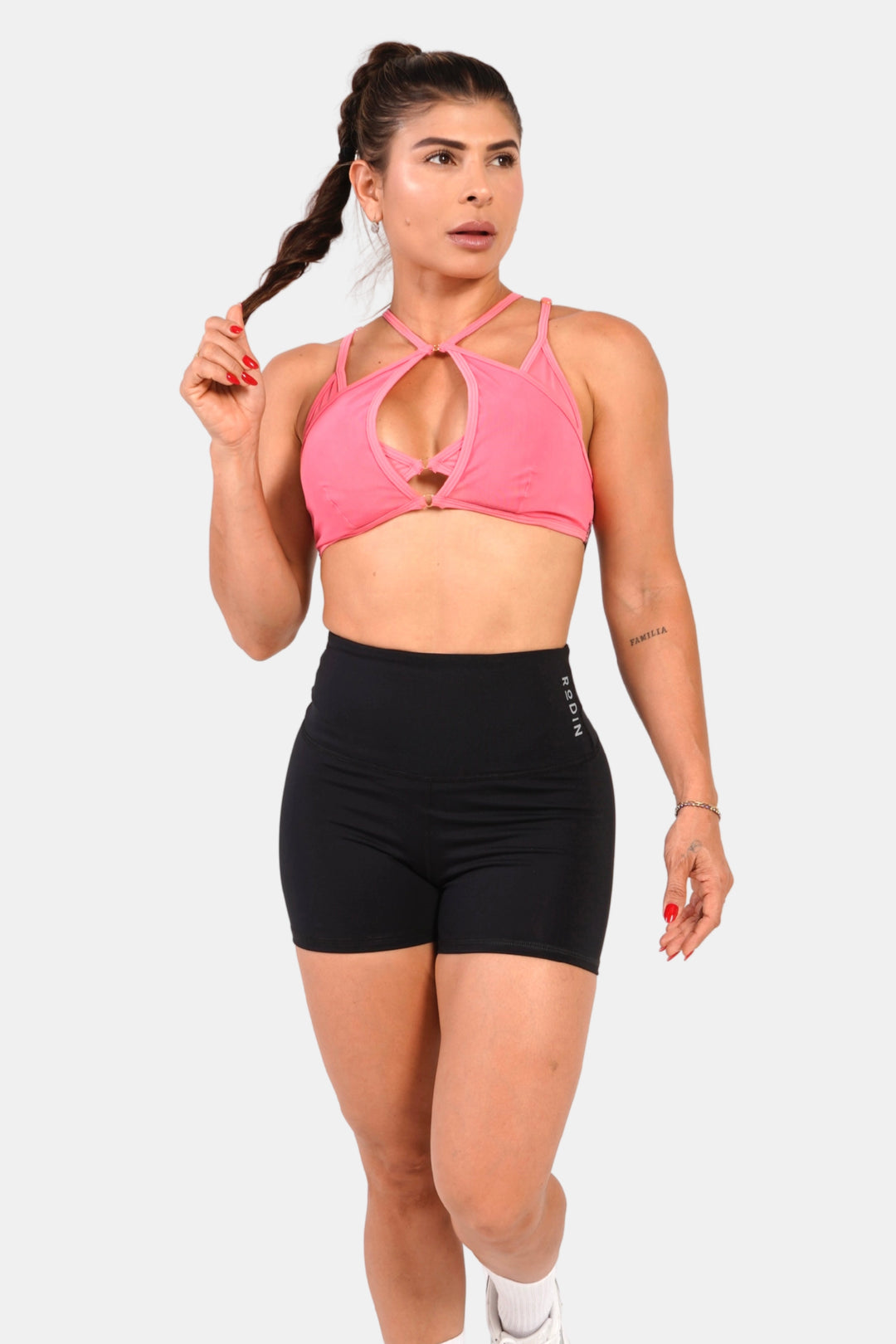 Woman wearing a pink sports bra and black shorts on a white background #color_rose