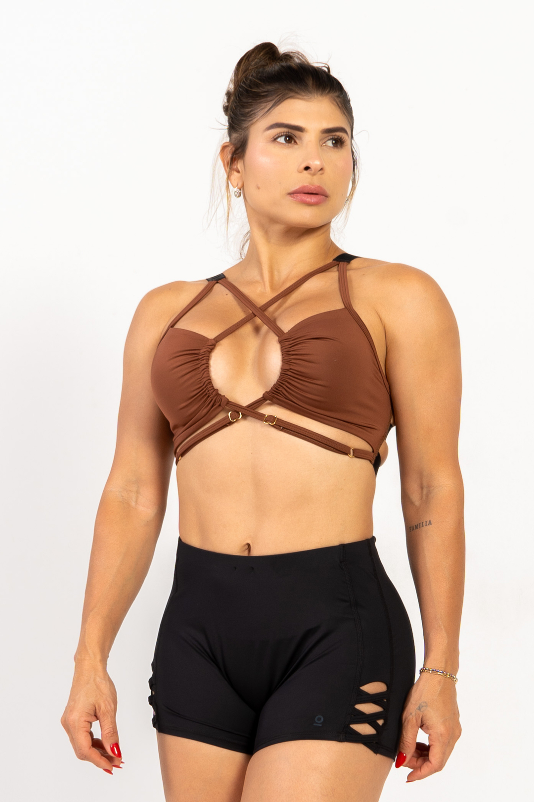 Woman wearing a brown strappy top and black shorts on a white background 
