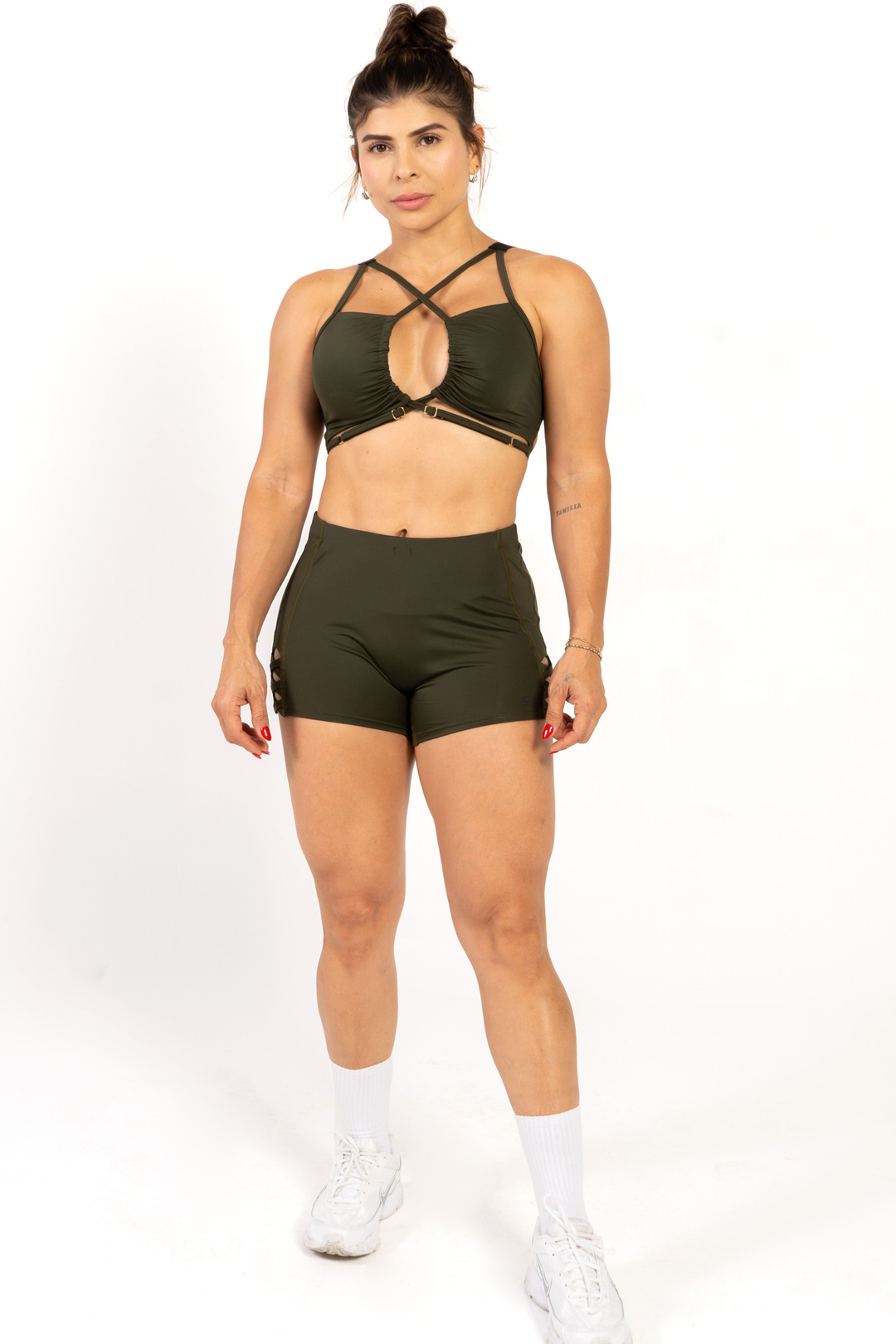 Woman wearing a green sports bra and shorts set on a white background 